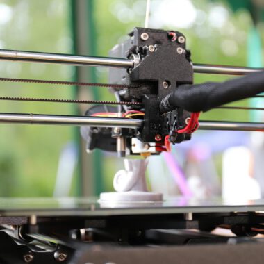 Detailed view of a 3D printer creating an object outdoors, highlighting innovation and precision.
